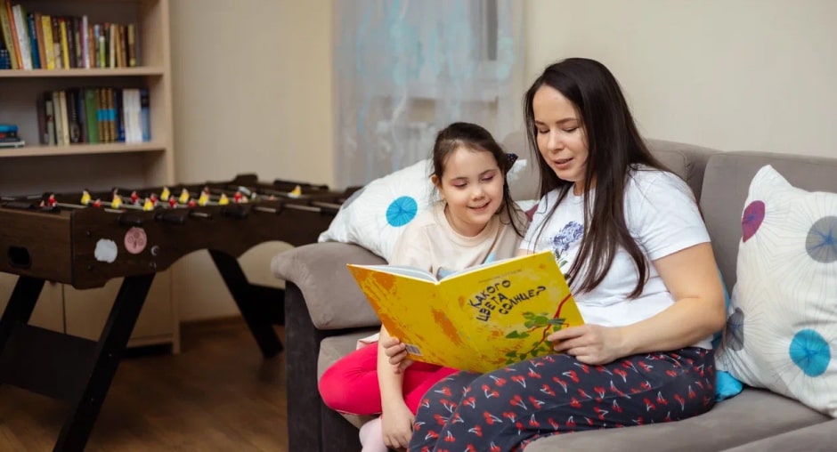 Женщина и девочка читают книгу на диване